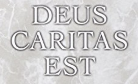 Texto con la frase en latín Deus Caritas Est en letras blancas con relieve sobre un fondo de mármol gris