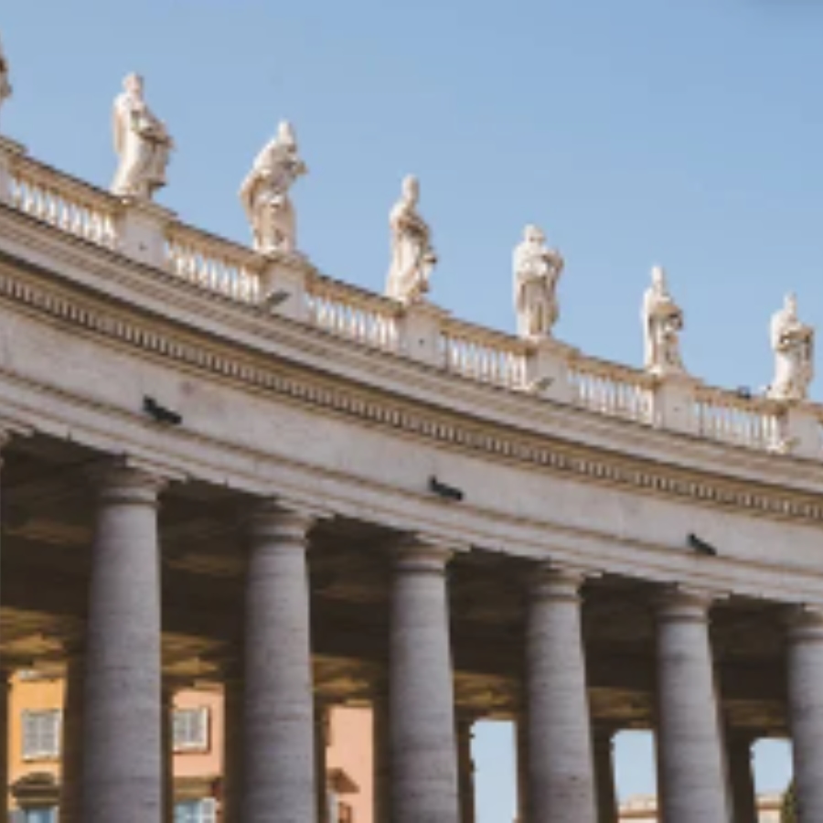 Vista en perspectiva de la columnata de Bernini en la Plaza de San Pedro con estatuas de santos sobre la balaustrada bajo un cielo despejado