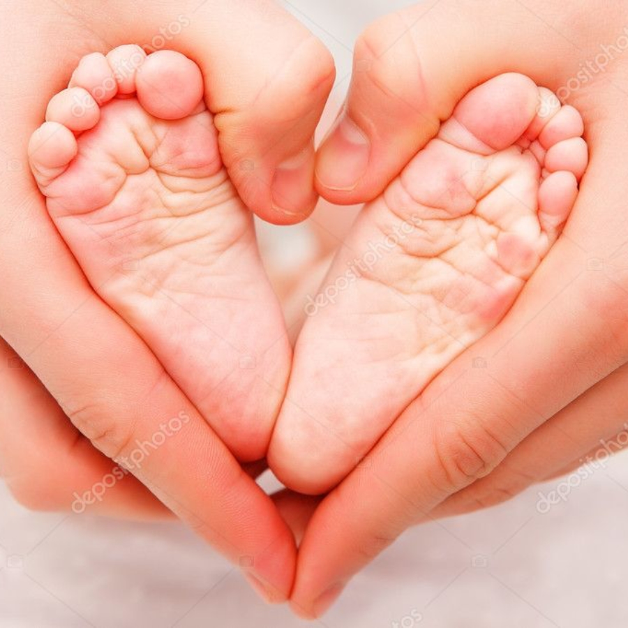 Fotografía en primer plano de manos de un adulto sosteniendo los pies de un bebé para formar la silueta de un corazón